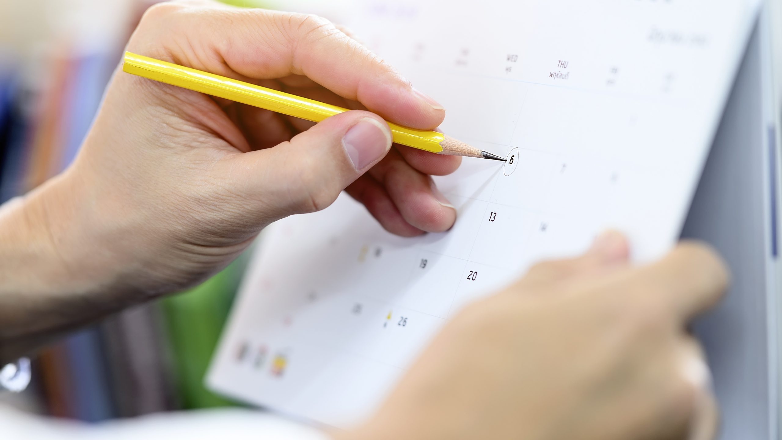 Cropped view of man hand holding yellow pencil writing on calend Kalendarz wydarzeń w Strefie Informacji Biznesowej WPT – maj 2023